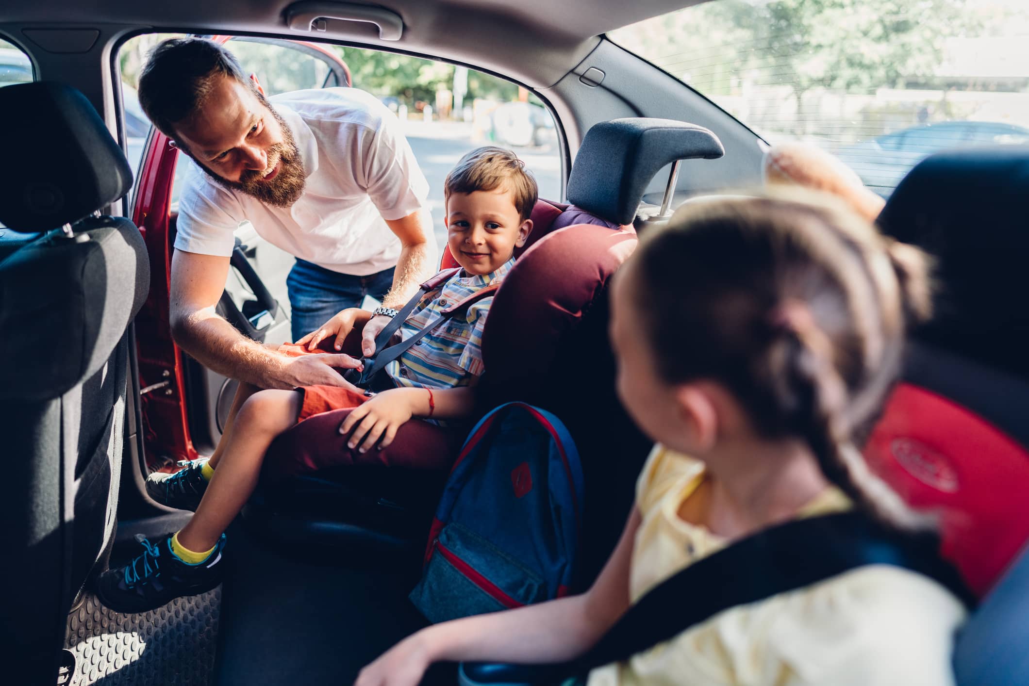 father buckling children into car